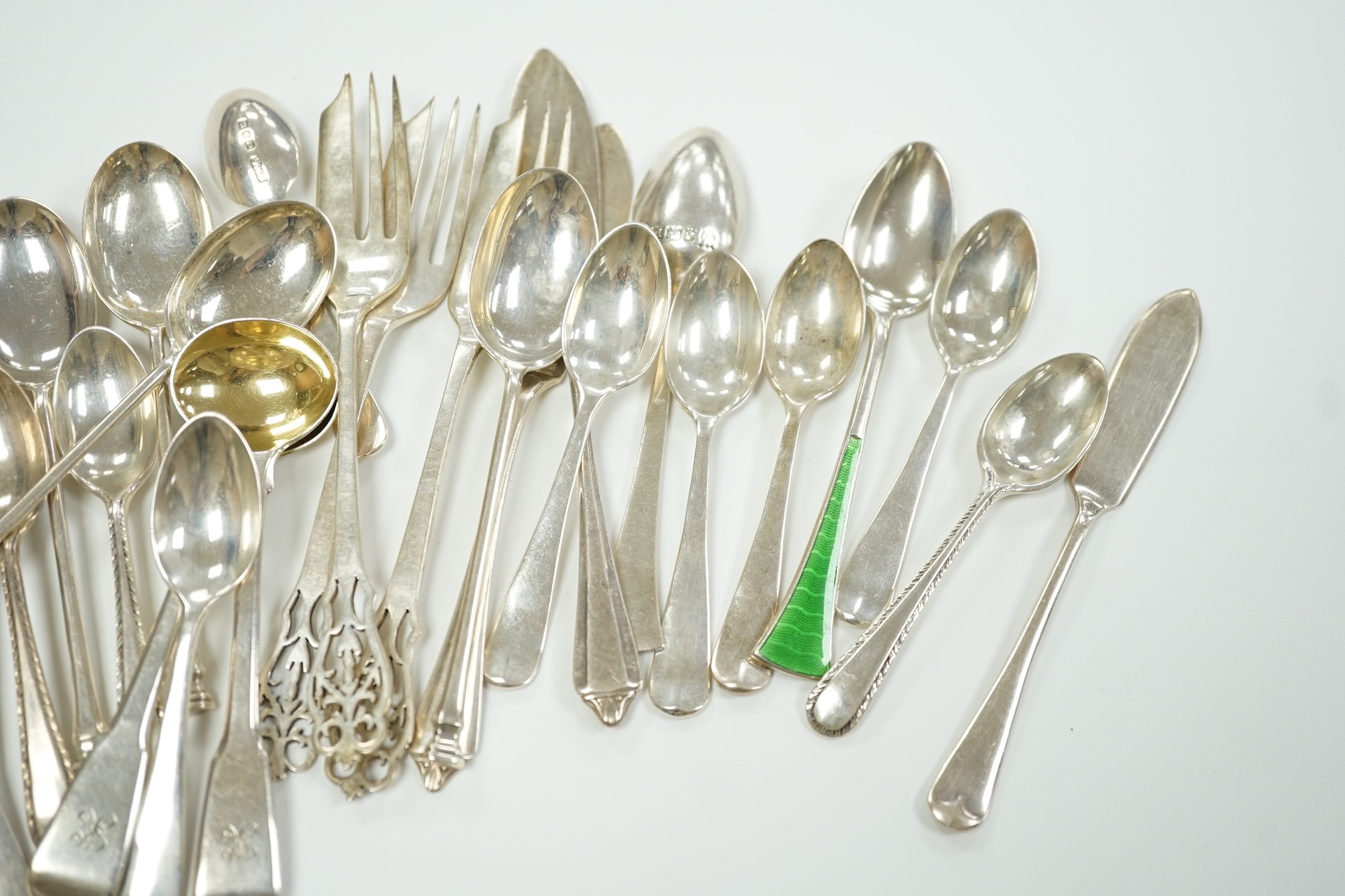 A small collection of assorted silver flatware including teaspoons, enamelled spoons(a.f.), butter knives, pastry forks and a pair of continental 830 white metal cake tongs, gross weight 14.4 oz.